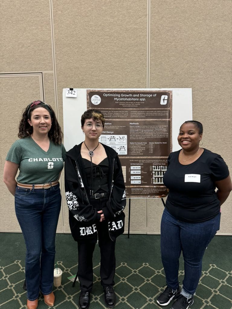 Three people smiling in front of a scientific poster on bacterial storage