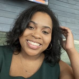 Headshot photo of a young Black woman smiling with medium-length black hair