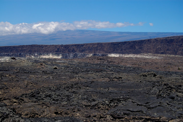 Photo taken by me from the Kilauea Caldera in 2007.  Mauna Loa (13000 ft elevation) looms in the background under a shroud of clouds, but it's shocking how small that 13000 ft mountain looks.