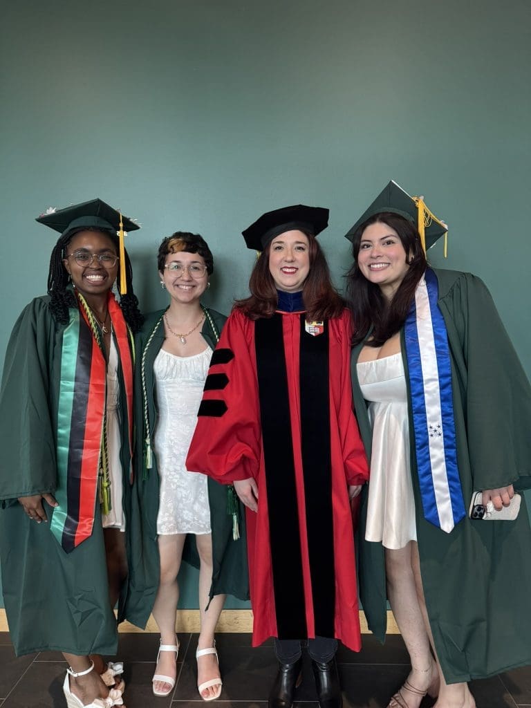 Four people in graduation robes smiling for a picture