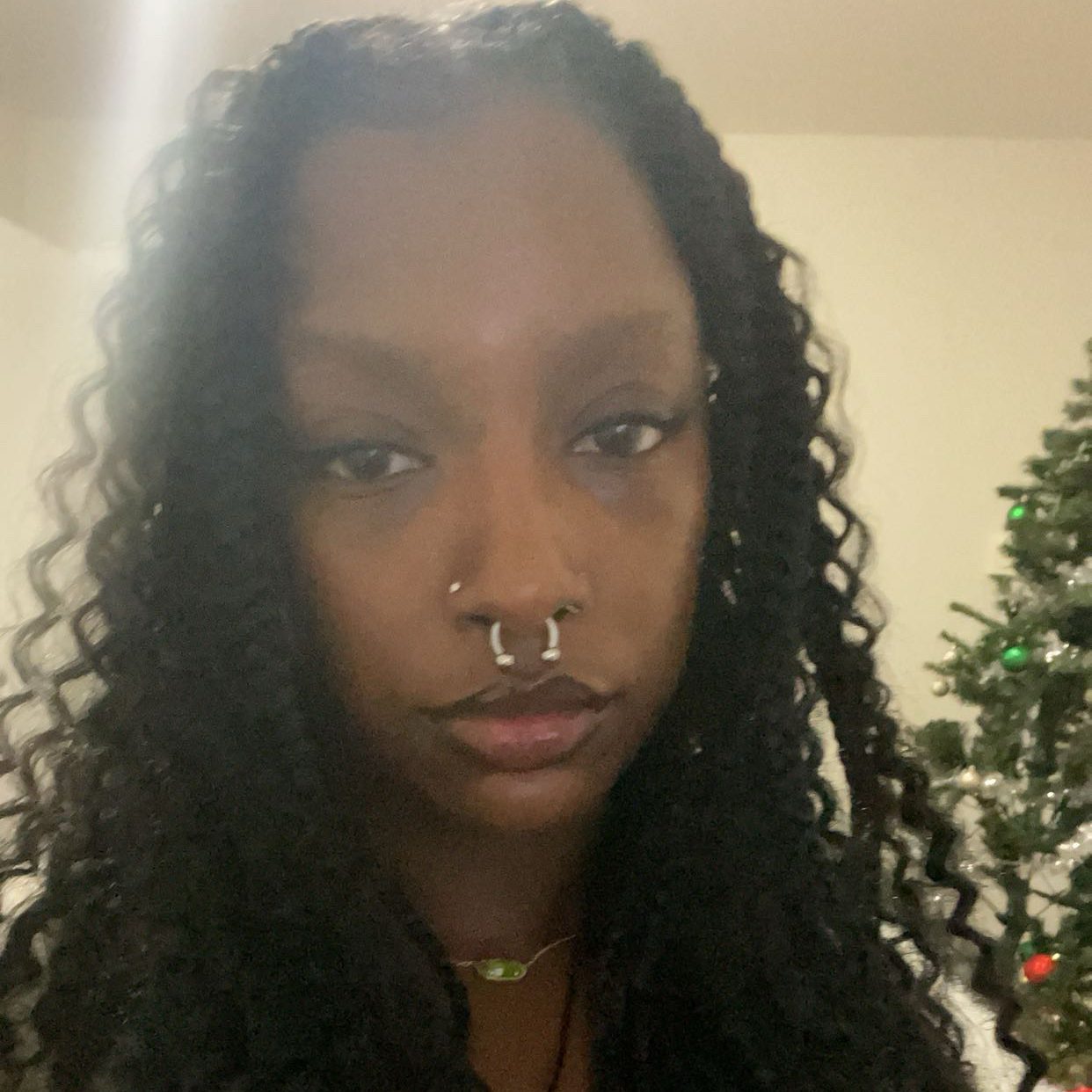 Headshot of a young Black woman with curly hair and various piercings